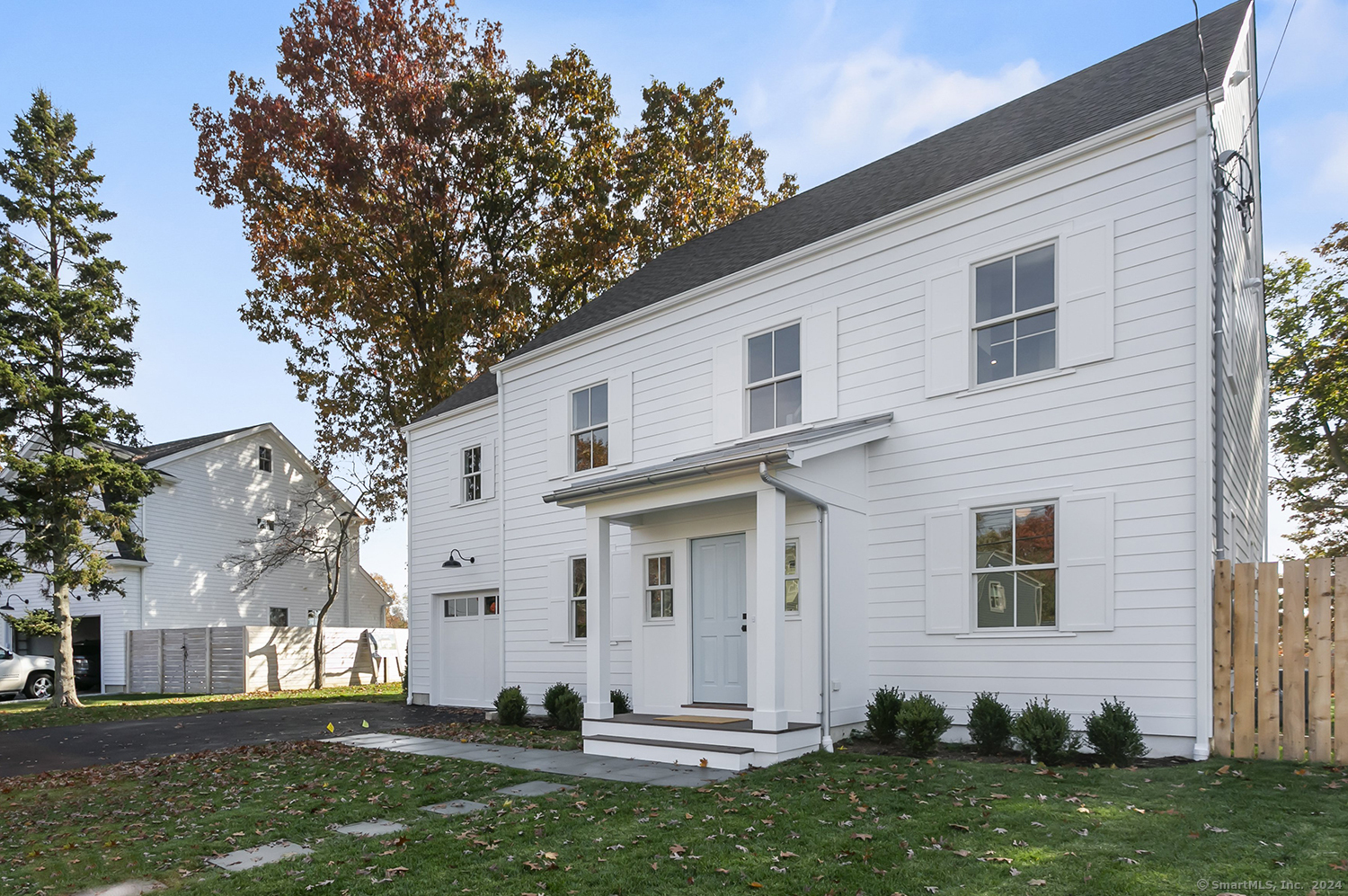 a view of a white house next to a yard with big trees