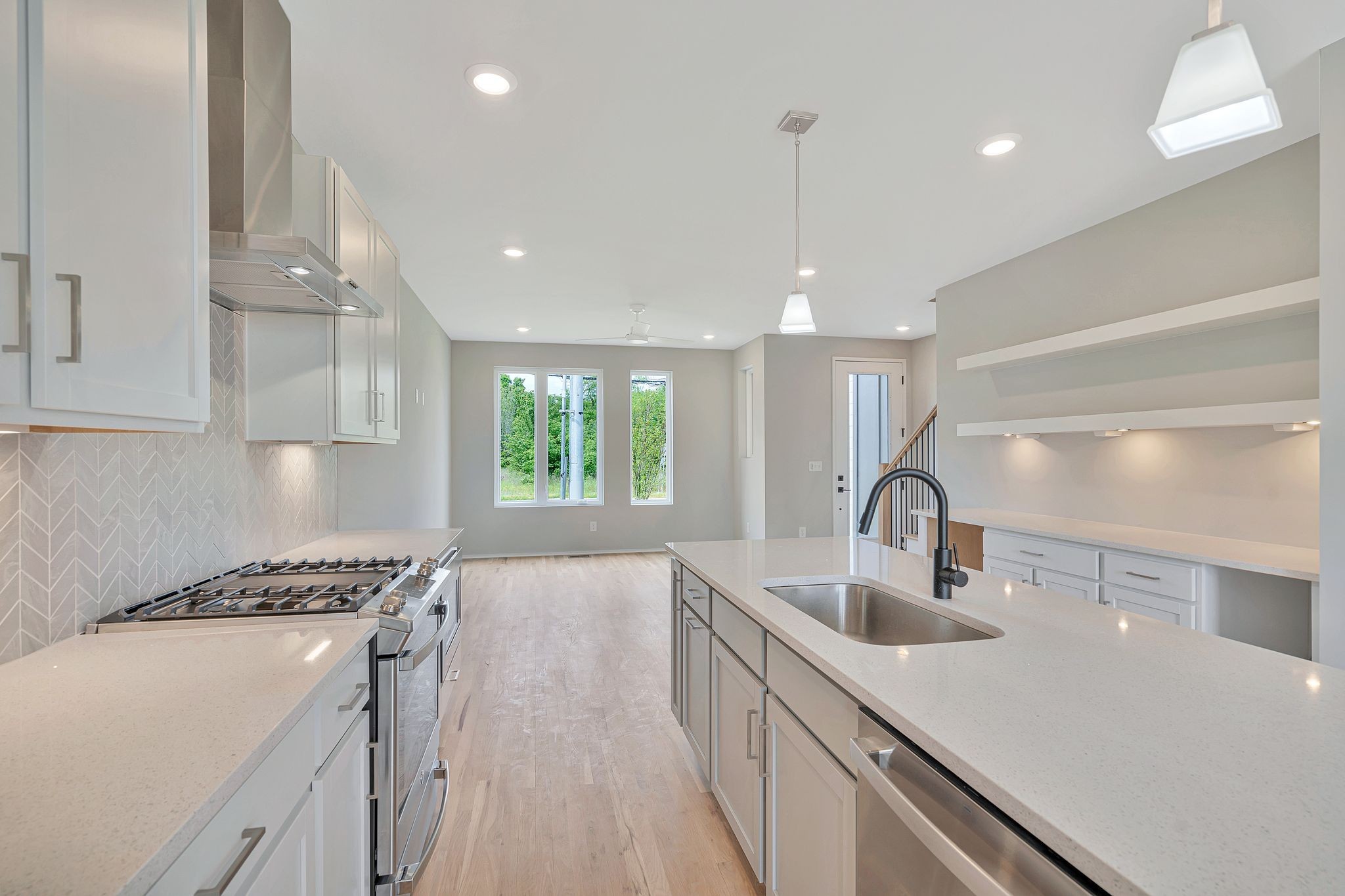 a kitchen with kitchen island stainless steel appliances a sink a stove and a wooden floors