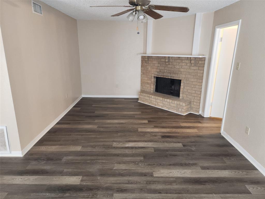 a view of an empty room with wooden floor and a fireplace