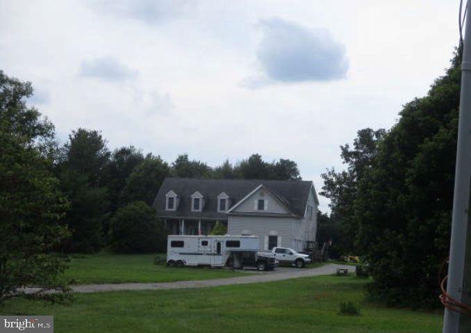 a view of a big house with a big yard plants and large trees