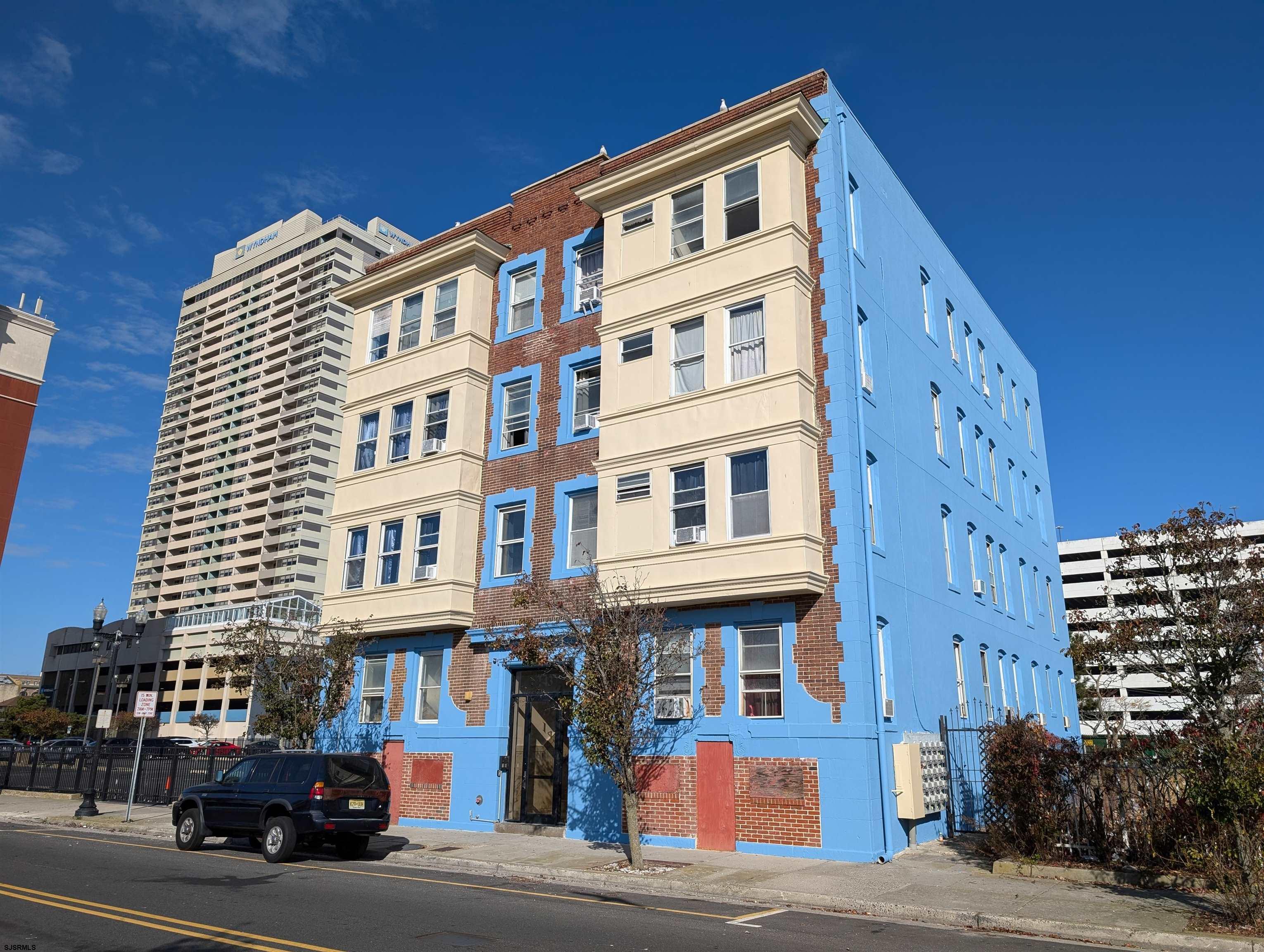 a front view of a building with lot of cars and trees