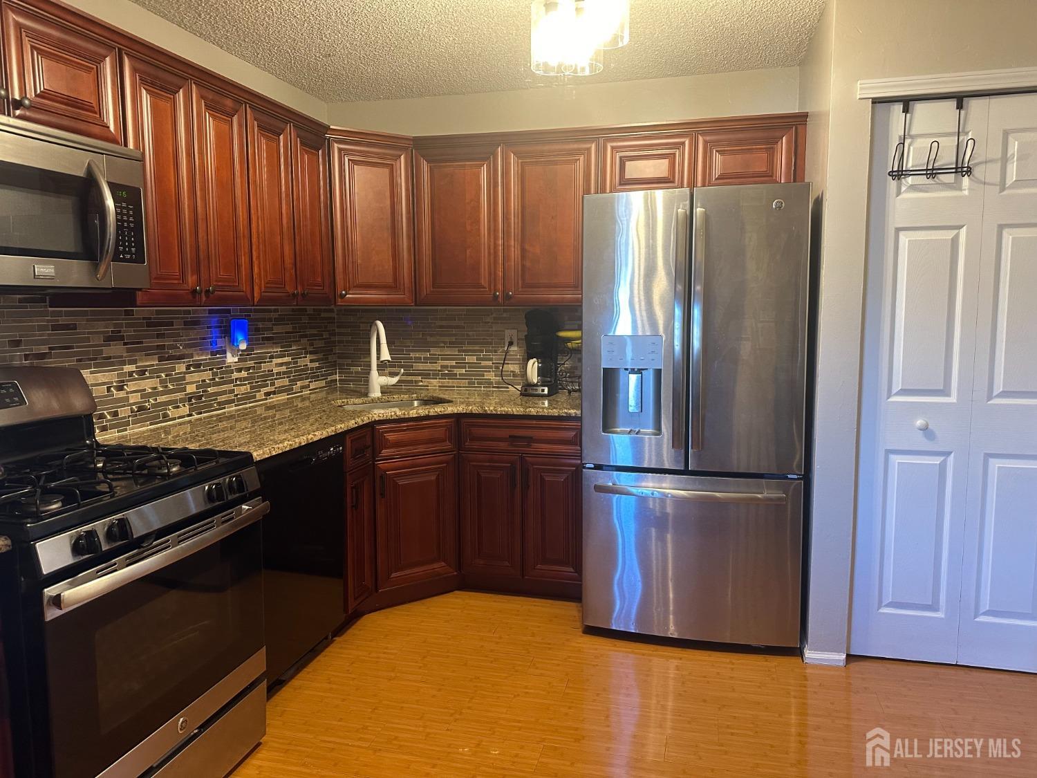 a kitchen with granite countertop wooden cabinets and stainless steel appliances