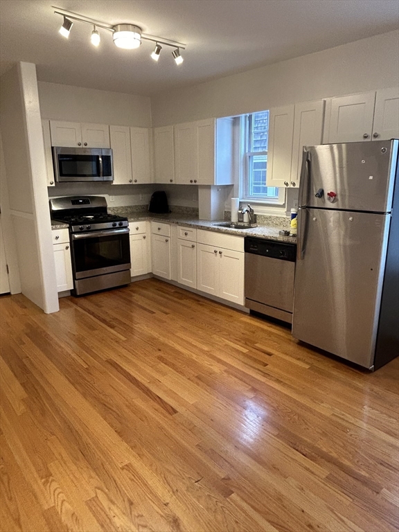 a kitchen with granite countertop a refrigerator and a stove top oven