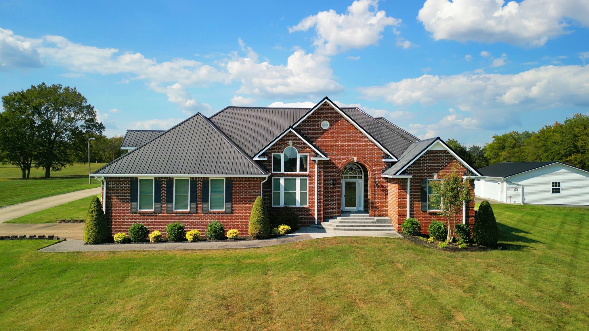 a front view of a house with a garden and trees