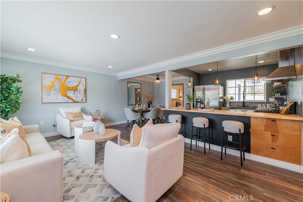 a living room with couches a coffee table and kitchen view with wooden floor