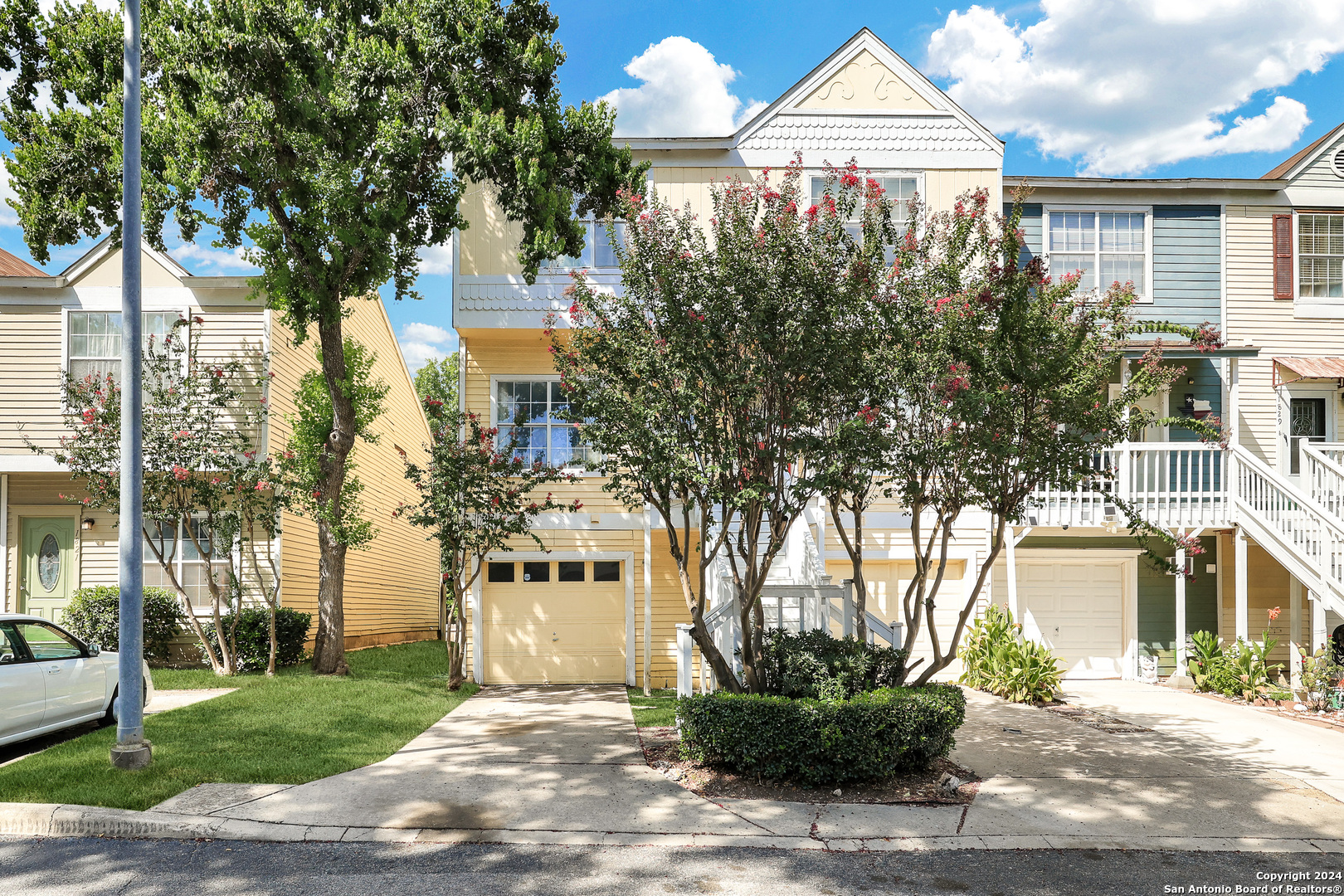 a front view of a house with a garden and trees