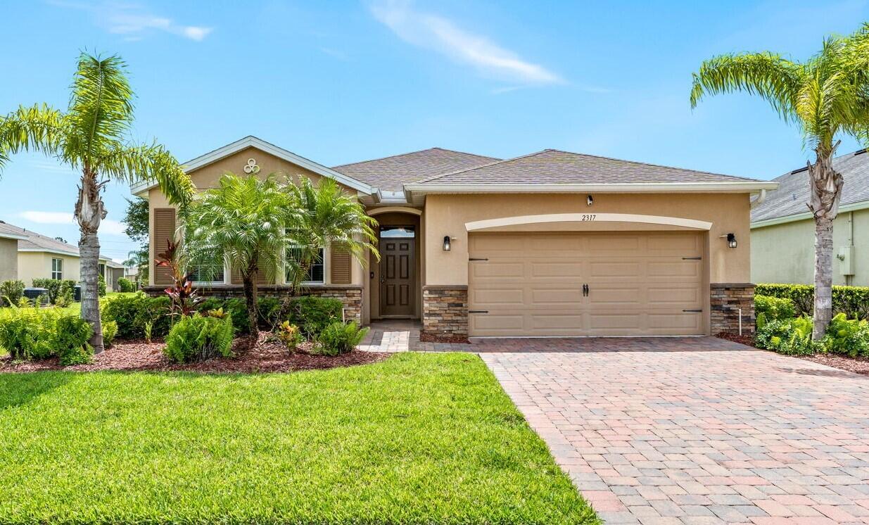 a front view of a house with a yard and potted plants