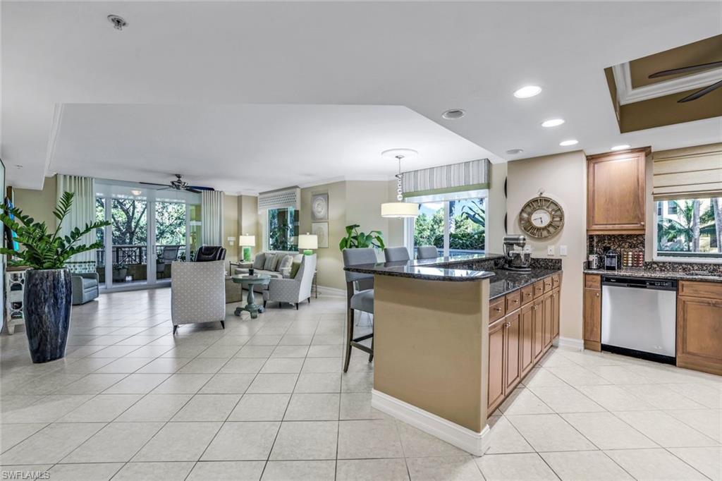 Kitchen with ceiling fan, pendant lighting, light tile patterned floors, dishwasher, and a kitchen bar