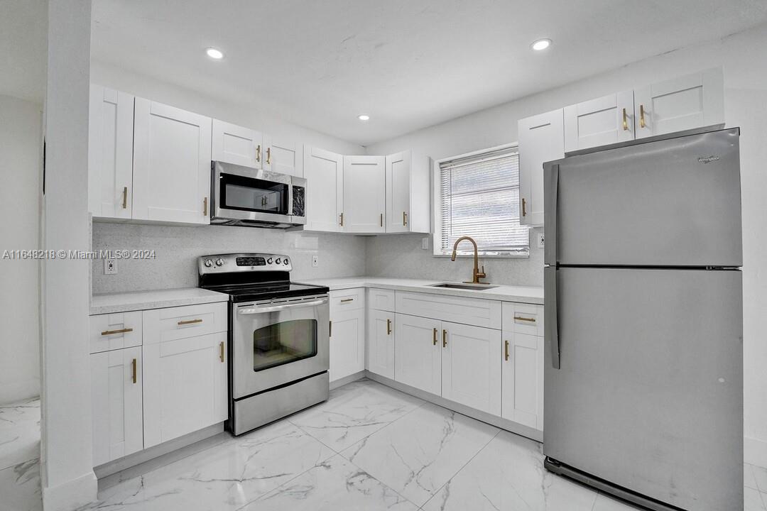 a kitchen with white cabinets sink and refrigerator