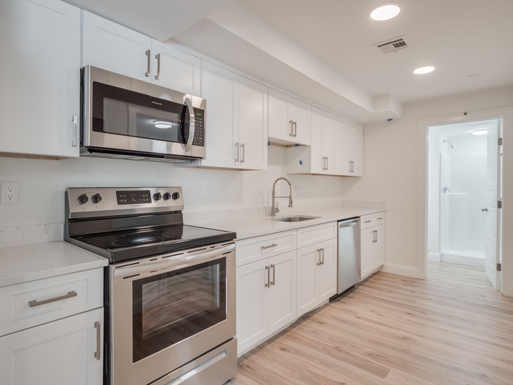 a kitchen with cabinets stainless steel appliances and wooden floor