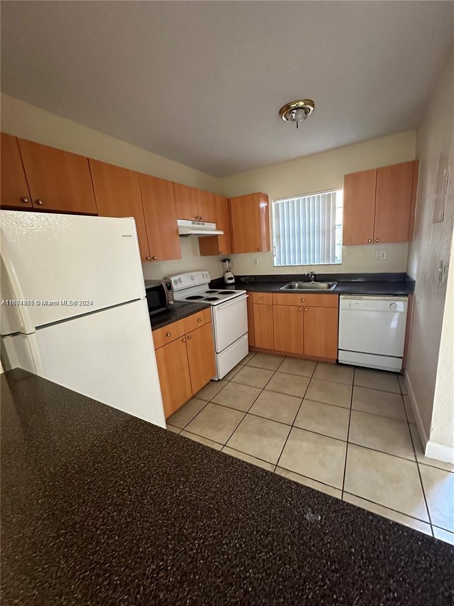 a kitchen with granite countertop a sink a stove top oven a counter space and cabinets