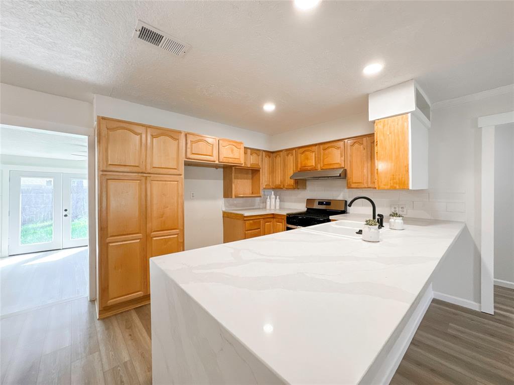 a large white kitchen with wooden floor and a sink