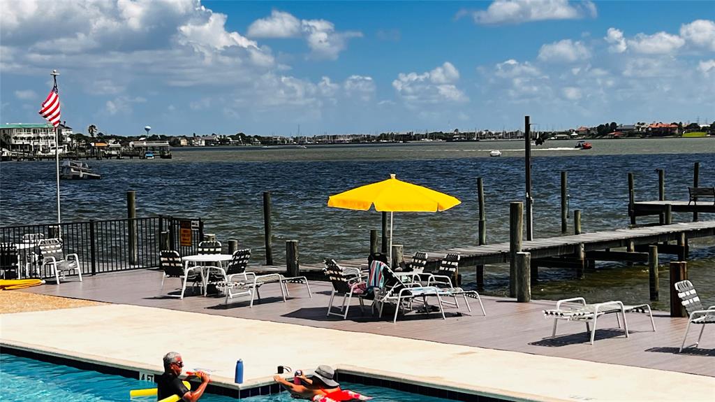 This waterfront property features a swimming pool with a lounging area and an adjacent private dock, offering direct access to a broad waterway. The location affords picturesque views and a setting ideal for boating and outdoor entertainment.