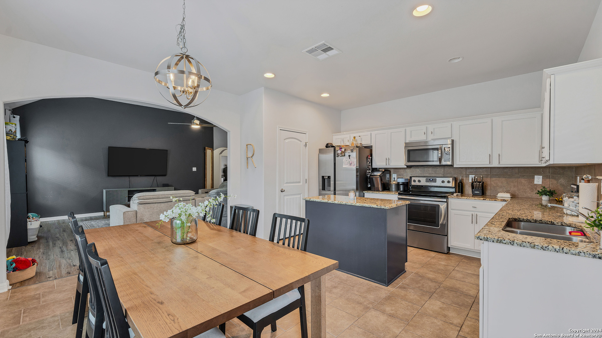 a kitchen with a dining table chairs and refrigerator