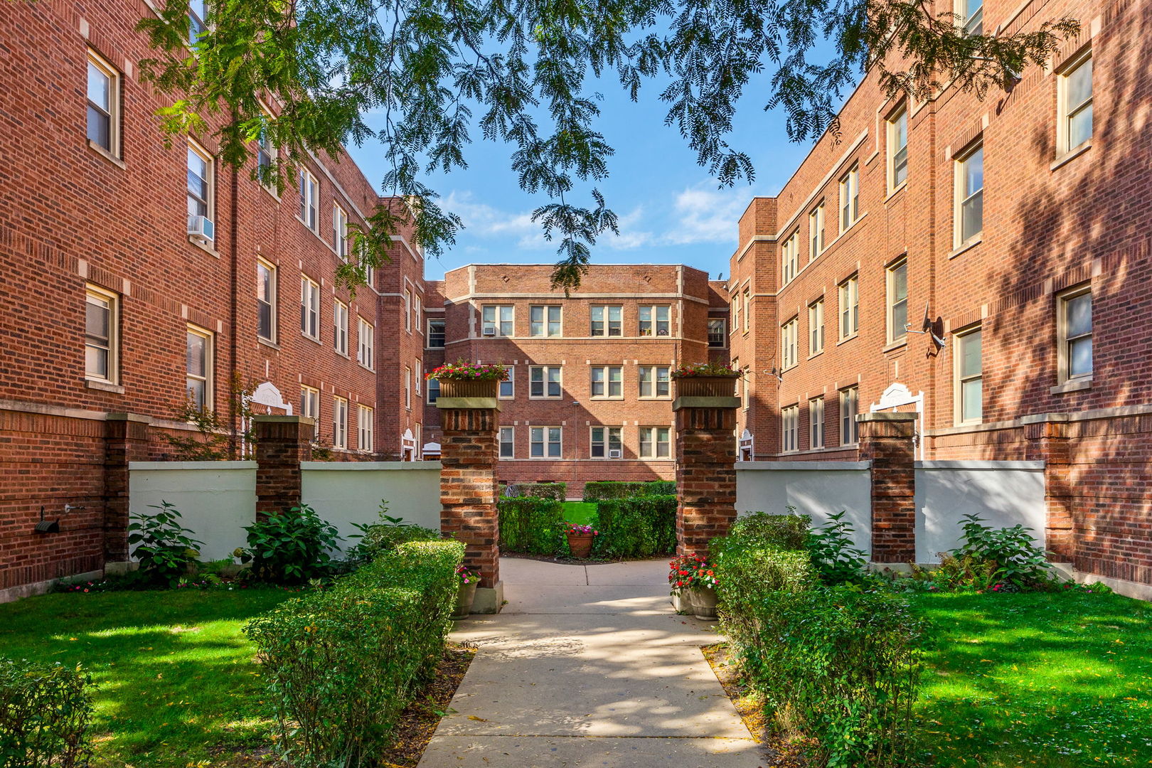 a front view of a multi story residential apartment building with yard and green space