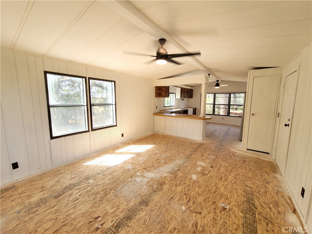 an empty room with chandelier fan and windows