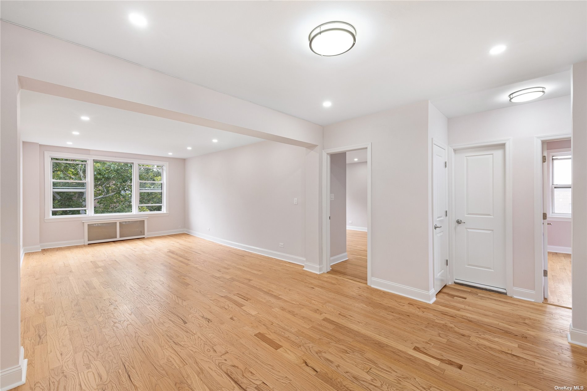 a view of an empty room with wooden floor and windows