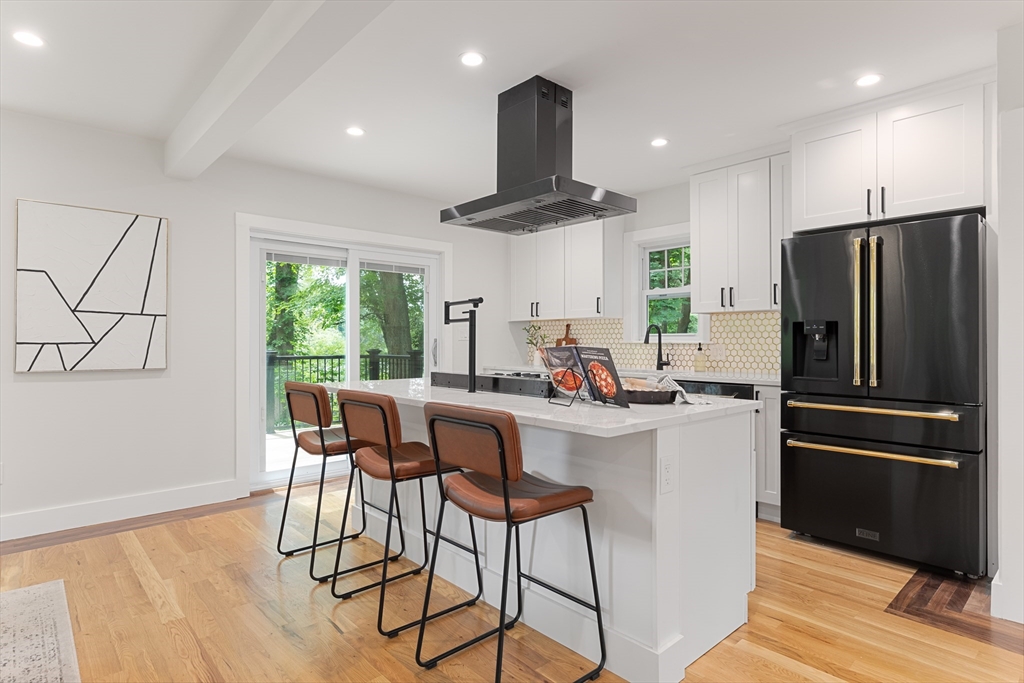 a kitchen with stainless steel appliances a dining table chairs refrigerator and cabinets