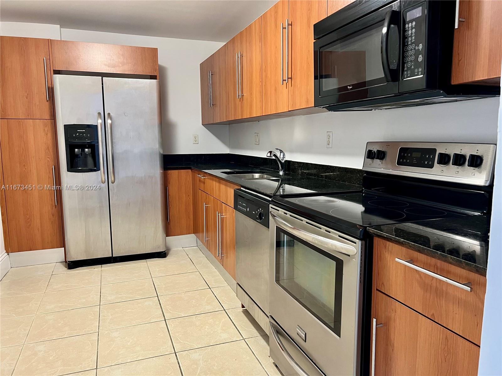 a kitchen with granite countertop a refrigerator and a microwave