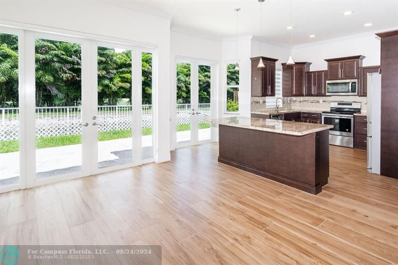 a view of kitchen with stainless steel appliances granite countertop a stove and a wooden floors