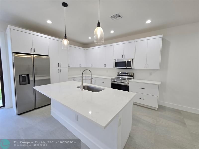 a kitchen with stainless steel appliances a refrigerator sink and microwave