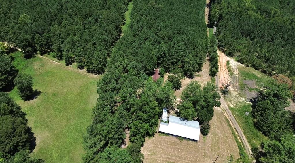 an aerial view of a house with a yard and trees all around