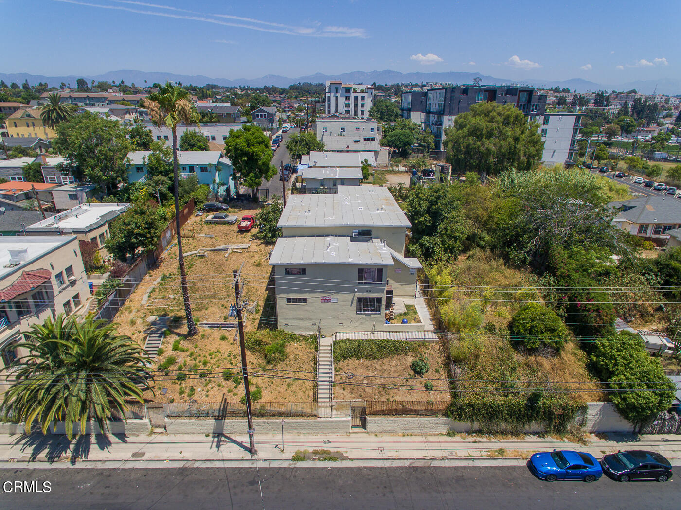 an aerial view of a residential apartment building with a yard and parking spaces