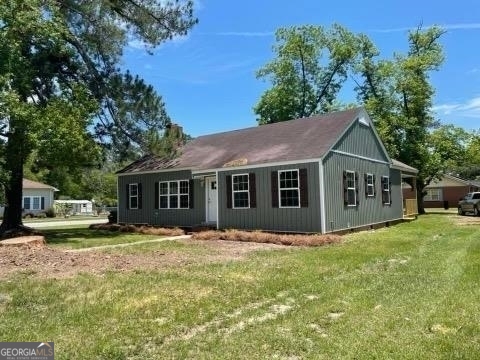 a front view of house with yard and trees in the background