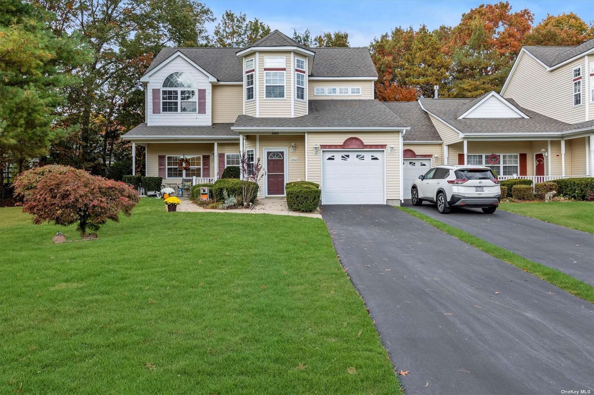 a front view of a residential houses with yard and parking