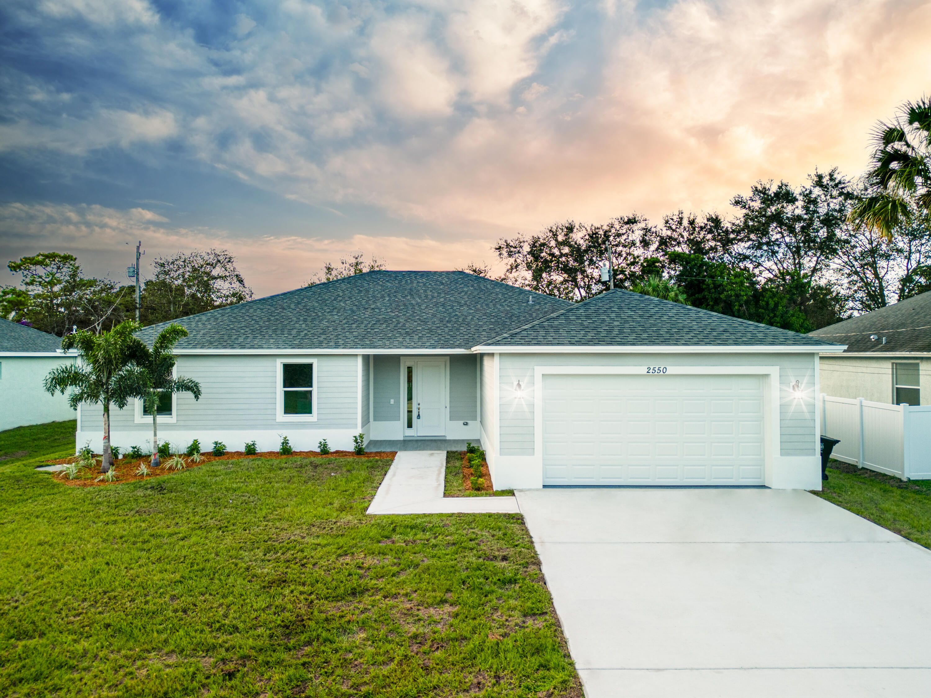 a front view of house with yard and trees in the background