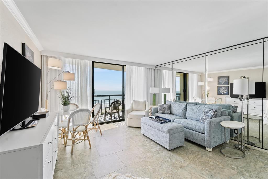 Enjoy coastal relaxation in this bright and inviting living room, complete with floor-to-ceiling windows that frame breathtaking Gulf of Mexico views. The mirrored wall enhances natural light, creating a spacious ambiance.