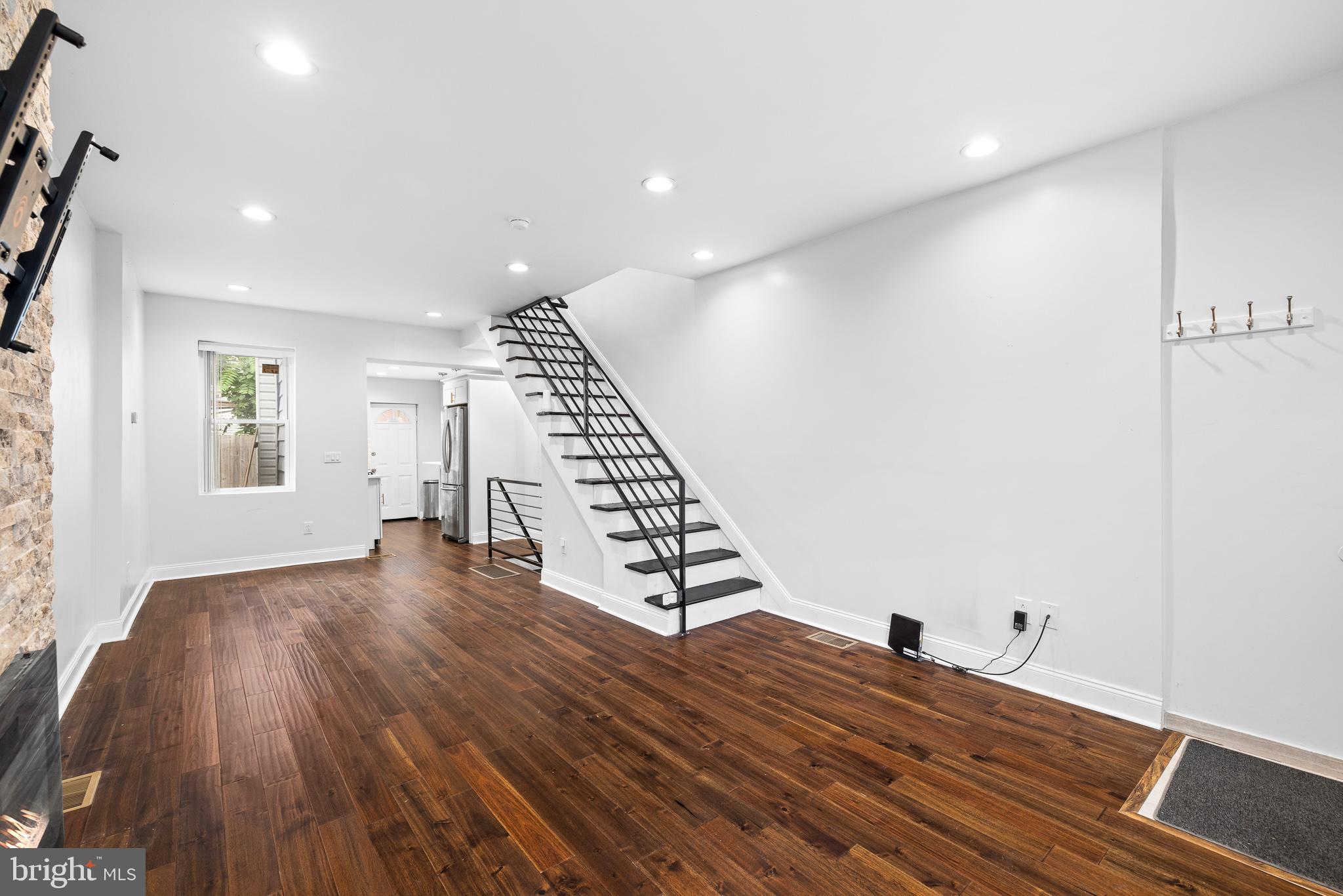 a view of a livingroom with wooden floor staircase and a kitchen