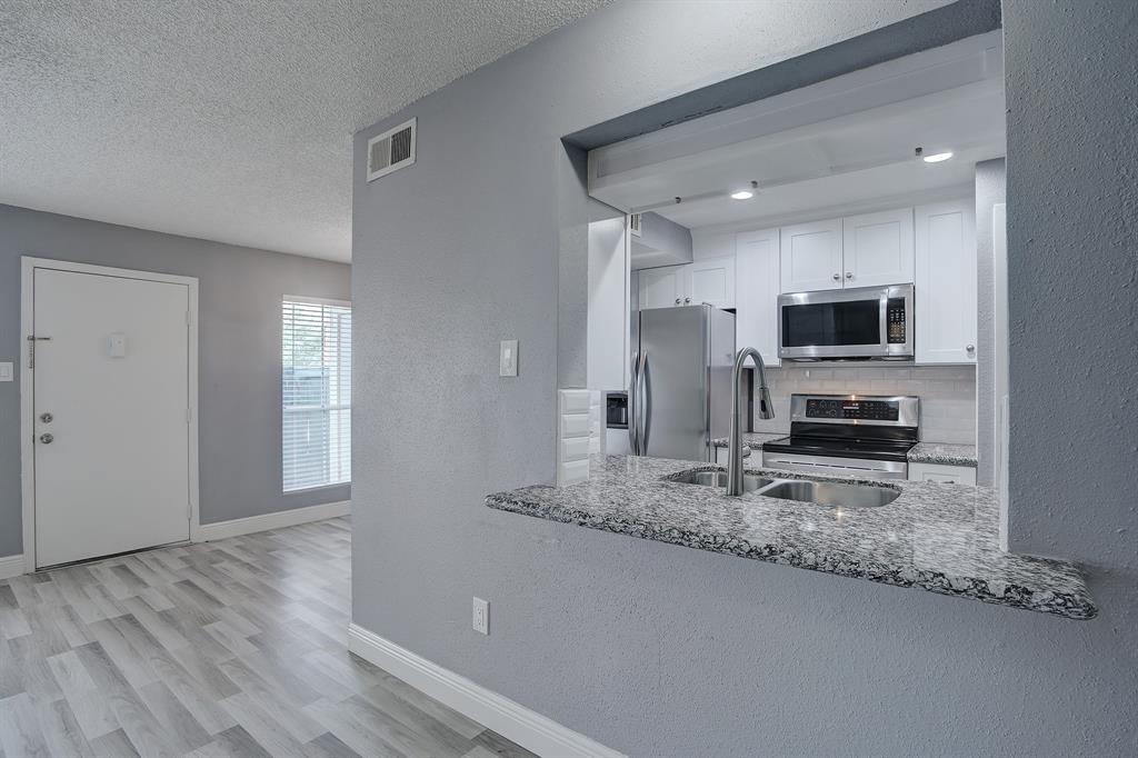 a living room with stainless steel appliances granite countertop a stove a sink and a granite counter tops