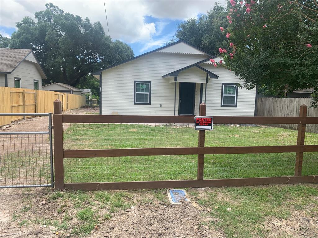 Front of nicely redone home showing new fence and gate. Notice new siding and roof.