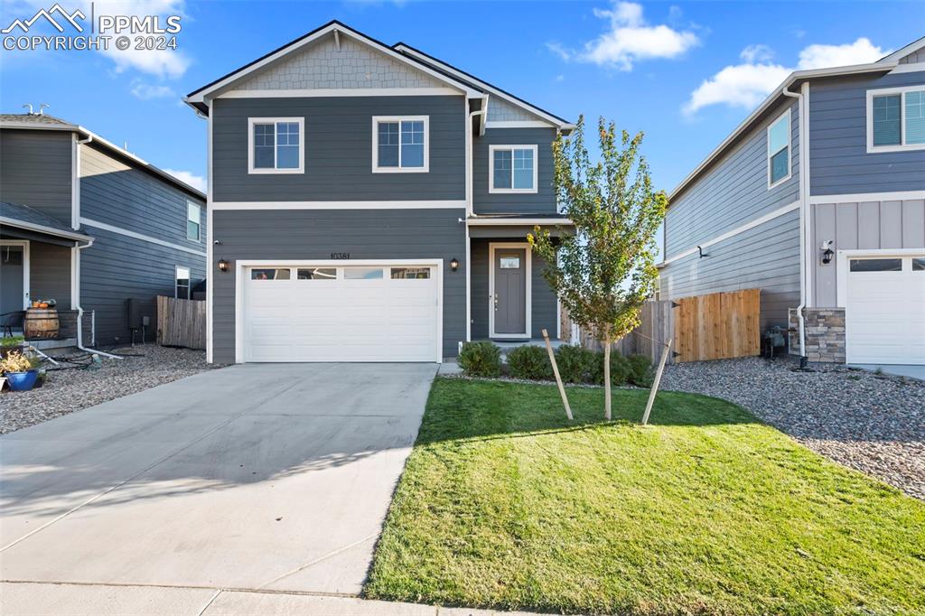 View of front of property featuring a front yard and a garage