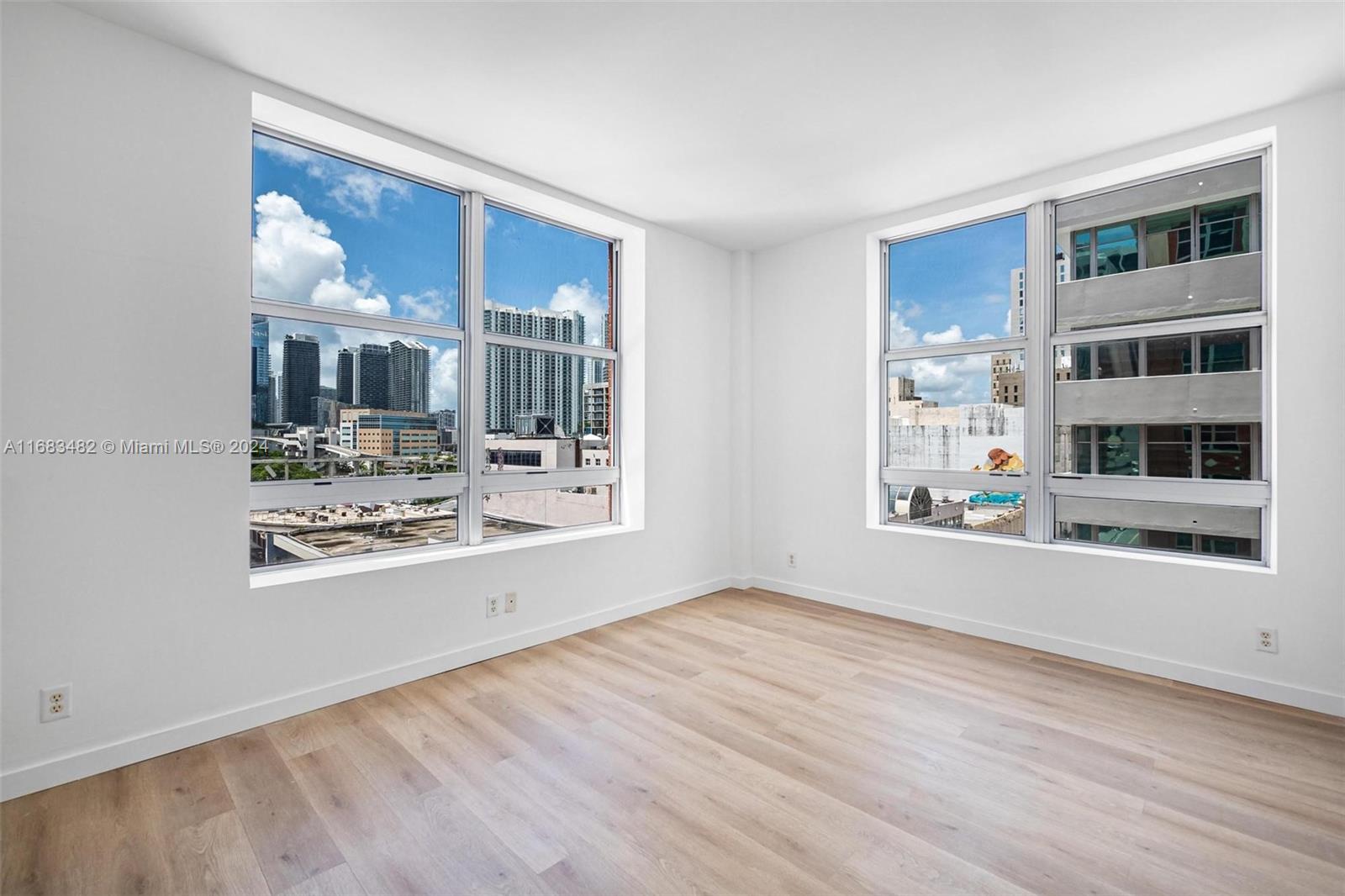 a view of an empty room with kitchen and window