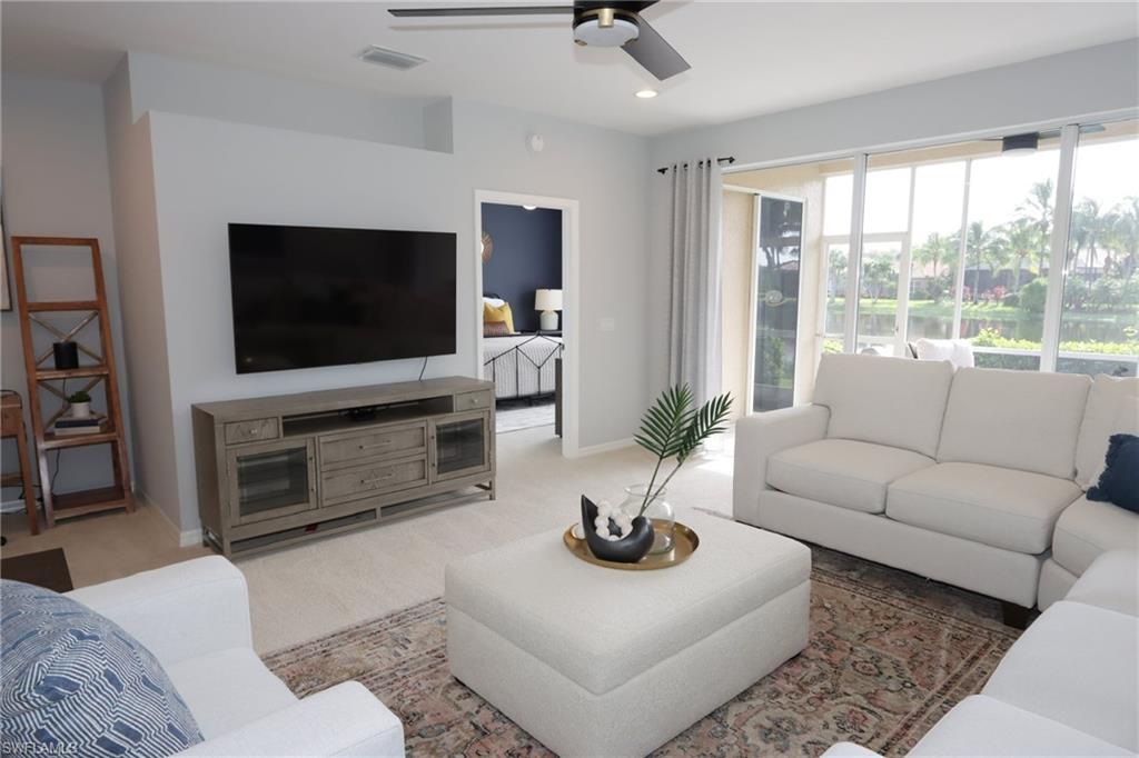 a living room with furniture a flat screen tv and a large window