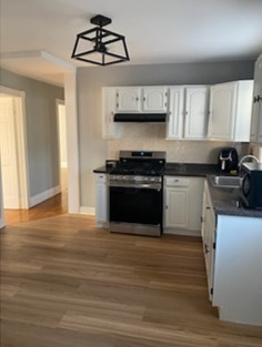 a kitchen with stainless steel appliances a stove a sink and white cabinets