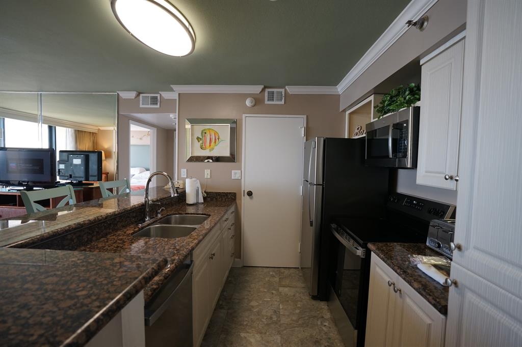 a kitchen with a granite countertop sink stove and refrigerator