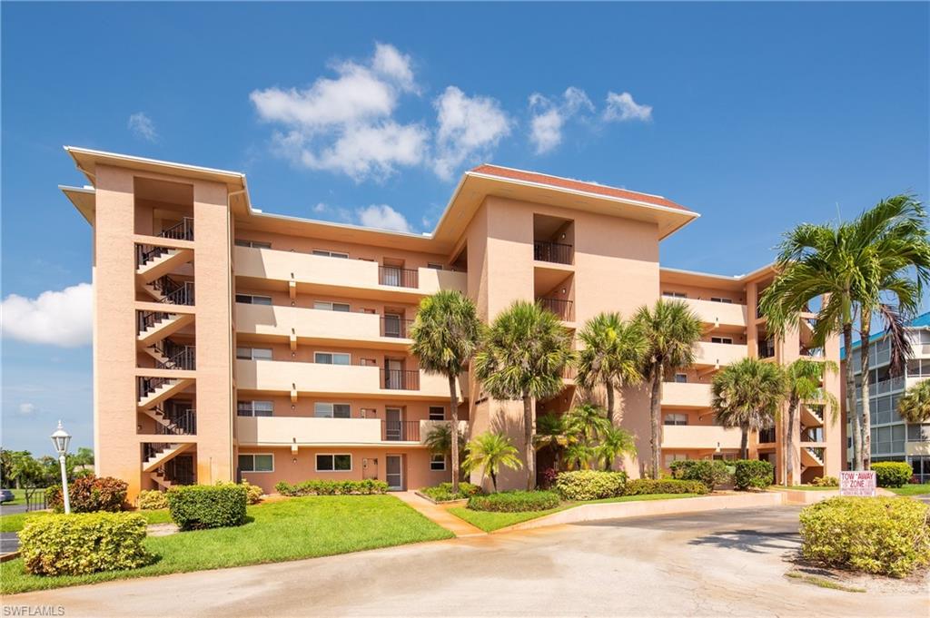 a front view of a multi story residential apartment building with yard and traffic signal