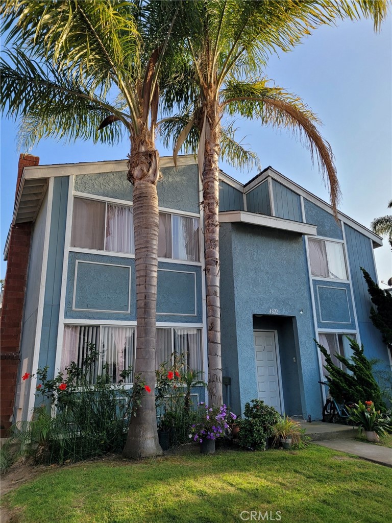 a front view of a house with a yard and palm trees