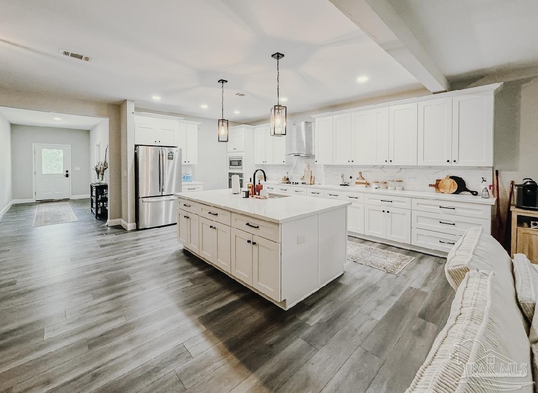 a kitchen with stainless steel appliances a sink wooden floor and cabinets