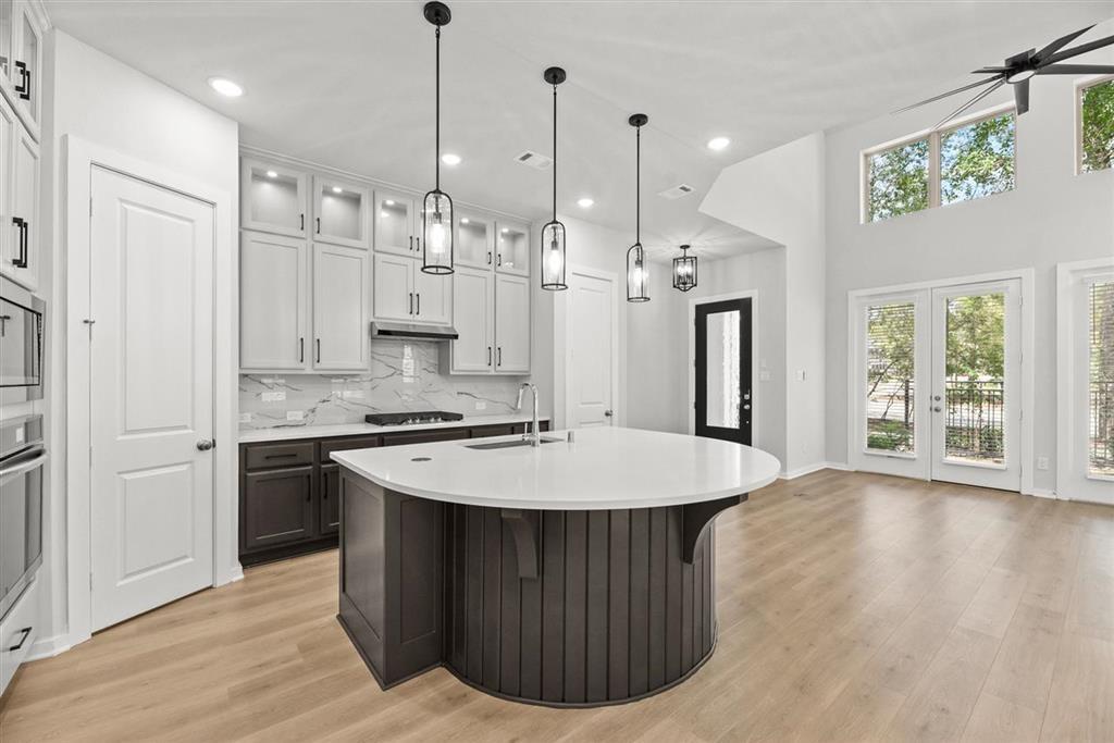 a kitchen with kitchen island a stove a refrigerator a sink a center island and wooden floor