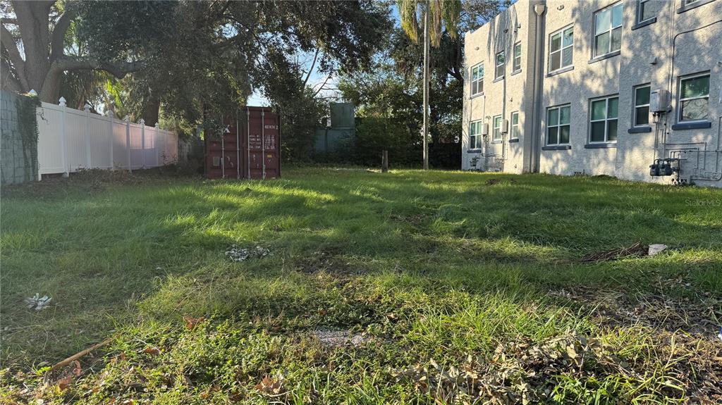 a view of a yard with plants and large trees