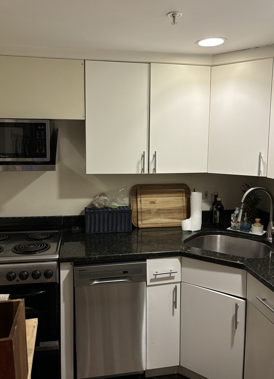 a kitchen with granite countertop white cabinets and black appliances