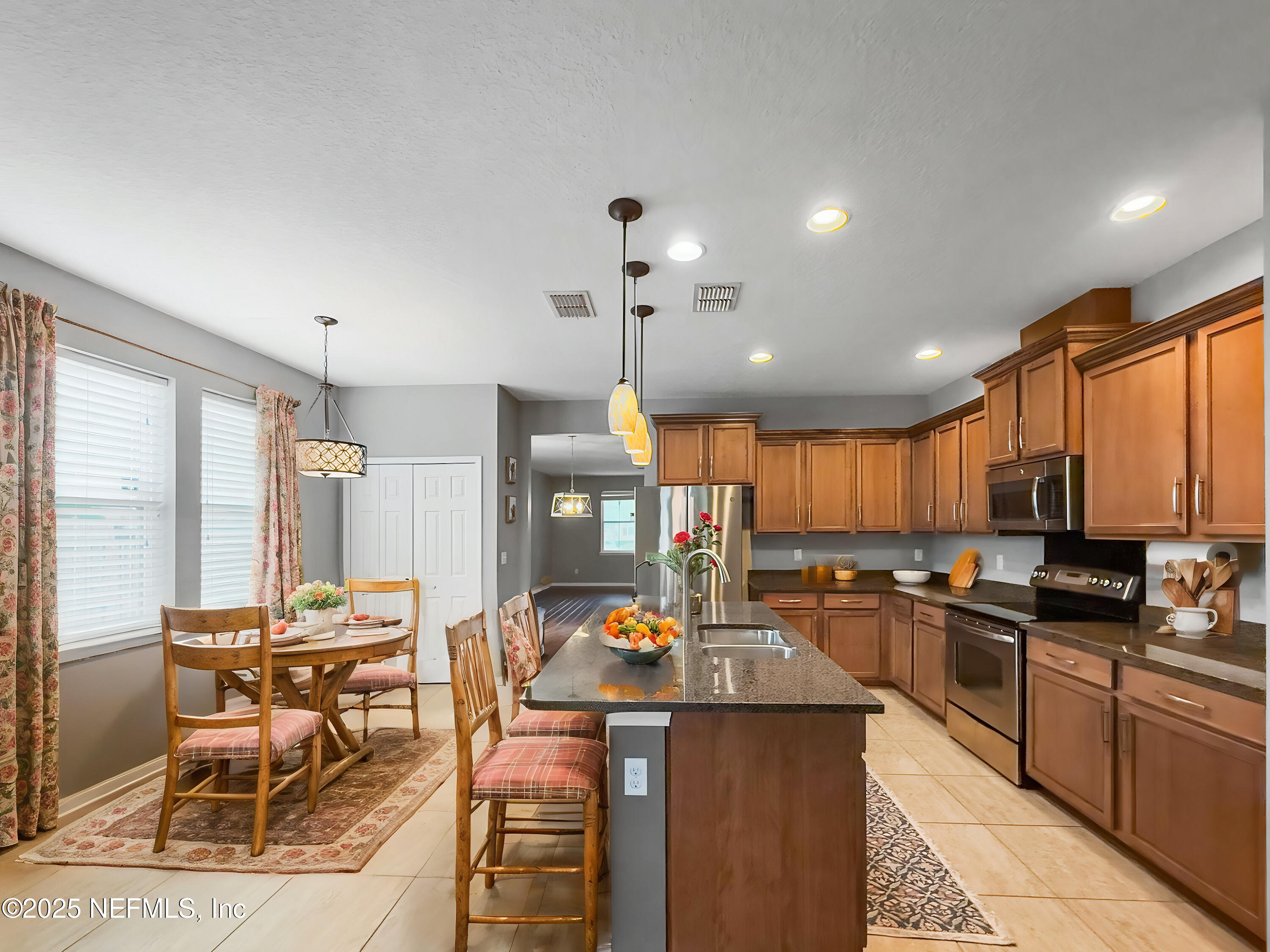 a kitchen with stainless steel appliances kitchen island granite countertop a stove top oven a sink a dining table and chairs