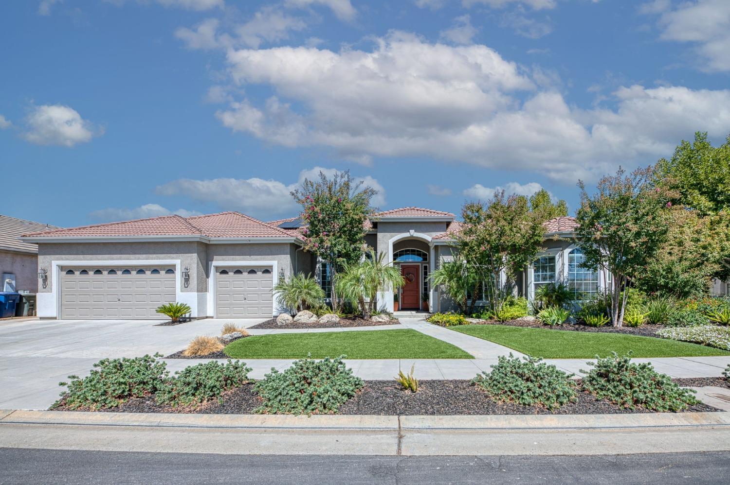 a front view of a house with a yard and potted plants