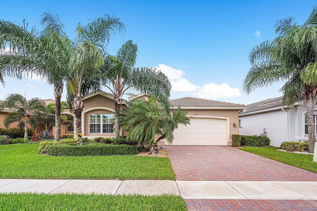 a front view of a house with a garden and palm trees