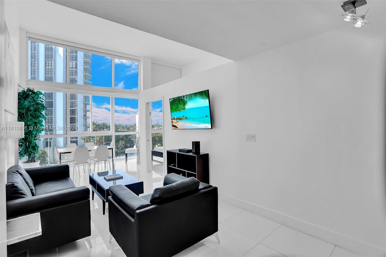 a living room with furniture a flat screen tv and a floor to ceiling window