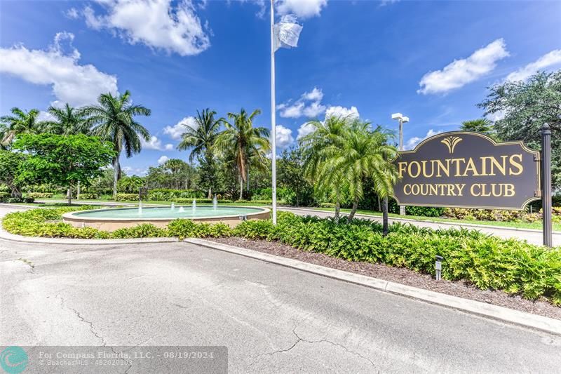 a view of a park that has a sign board with plants